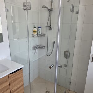 מקלחון זכוכית עם מוצרי רחצה על מדף