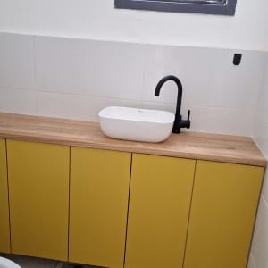 כיור לבן עם ברז שחור על ארון עץ צהוב