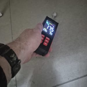 מד לחות על רצפה, יד מחזיקה את המכשיר