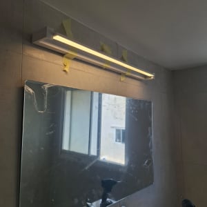 מראה עם תאורה מותקנת בחדר אמבטיה