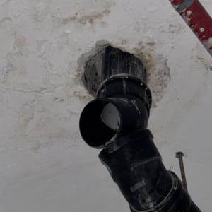 צינור שחור מותקן בתקרה עם סימני רטיבות