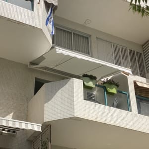 סוככים לבנים על מרפסות בניין עם צל