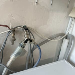 צינורות ומחברים על קיר ליד מכשיר חשמלי