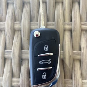 מפתח רכב עם שלושה כפתורים על רקע עץ