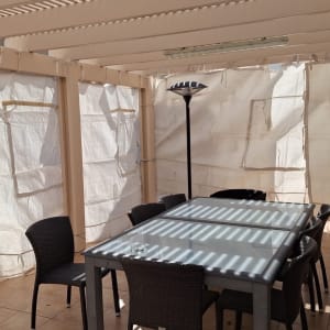 שולחן וכיסאות תחת פרגולה עם קירות בד