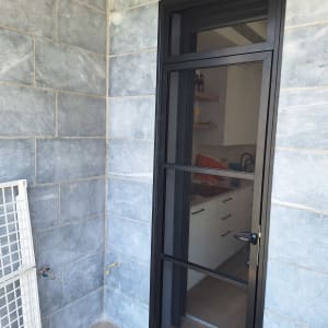 דלת אלומיניום שחורה על רקע קיר אפור
