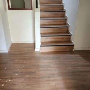 מדרגות ורצפת עץ בבית עם מעקה מתכת.