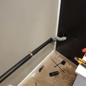 צינור פלסטיק שחור עם מחבר מתכת על קיר