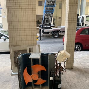 יחידת מזגן חיצונית עם מאוורר כתום ומנוף ברקע