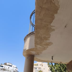 מרפסת עם קיר מתקלף ועצים ברקע