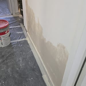 קיר צבוע חלקית עם דלי צבע על הרצפה