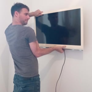 אדם מתקין טלוויזיה על הקיר