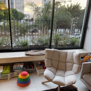 חדר עם כיסא, צעצועים וחלון גדול עם נוף עירוני