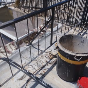 מסגרת מתכת שחורה על גג עם דלי וצבע