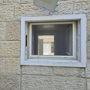 חלון אלומיניום עם מסגרת לבנה על קיר אבן