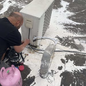 טכנאי מתקין מזגן עם בלון גז על הגג