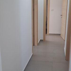 מסדרון עם קירות לבנים ודלתות עץ בהירות