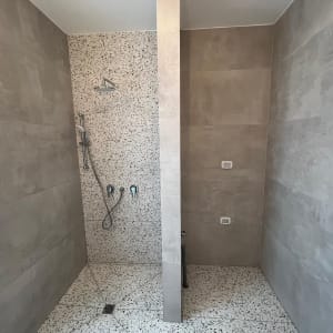 מקלחת משופצת עם אריחים אפורים וברזים חדשים