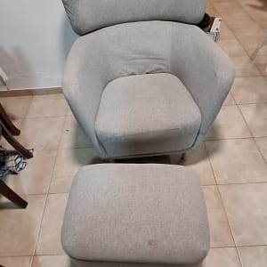 כורסה אפורה עם הדום על רצפת אריחים