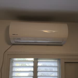 מזגן מותקן על קיר מעל חלון עם תריסים