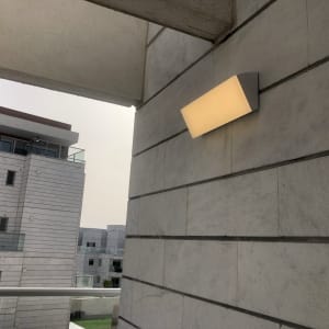 מנורת קיר מוארת על קיר חיצוני