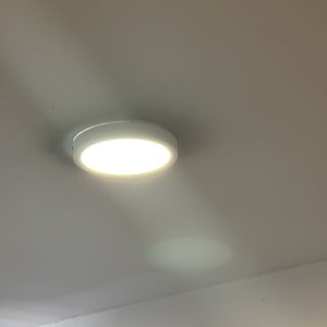 מנורת תקרה עגולה דולקת על תקרה לבנה