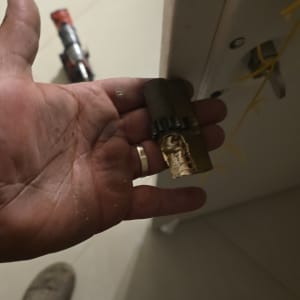 יד מחזיקה צילינדר מנעול שבור ליד דלת