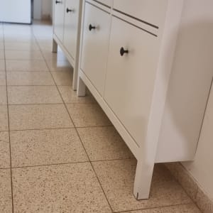 ארון לבן עם ידיות שחורות על רצפת אריחים