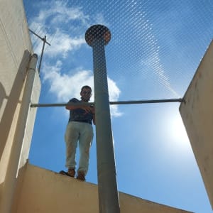 אדם עומד על גג עם רשת למניעת יונים