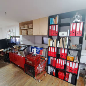 מדפים עם קלסרים אדומים, סלסלות קש ומדפסת במשרד