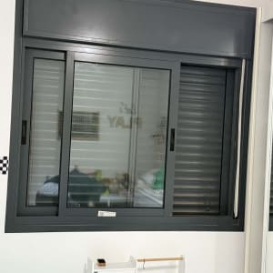 חלון עם תריסים אפורים בחדר פנימי