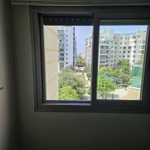 חלון אלומיניום עם נוף של בניינים ועצים