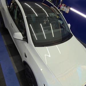 רכב לבן בחדר דיטיילינג עם ציוד לטיפוח הרכב