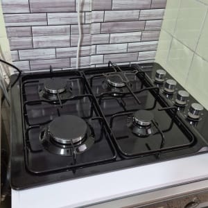 כיריים גז עם כפתורים על רקע קיר אריחים