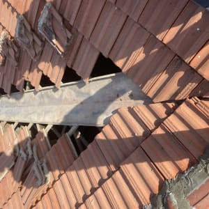 רעפים שבורים על גג עם קרשים חשופים