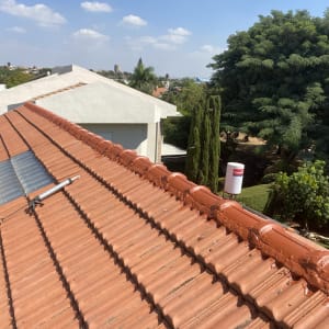 גג רעפים אדום עם לוחות שקופים וצינור מתכת