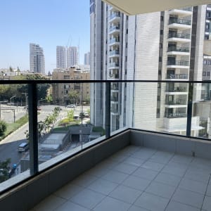 מרפסת עם רצפת אריחים נקייה ומעקה זכוכית