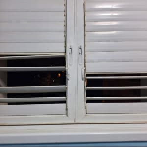 תריסים לבנים פתוחים למחצה עם ידיות מתכת