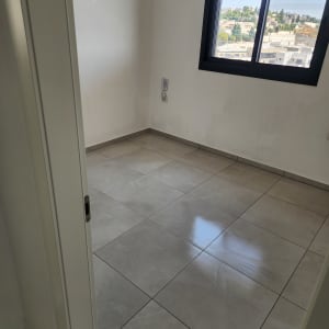 חדר ריק עם רצפת אריחים נקייה וחלון פתוח
