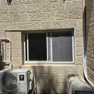 חלון אלומיניום עם מסגרת לבנה על קיר אבן