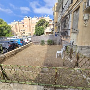 חצר קטנה עם גדר מתכת וכיסא פלסטיק