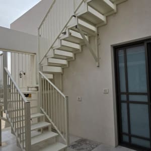 מדרגות חיצוניות עם מעקה מתכת לבן