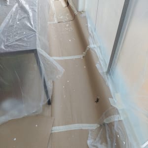 רצפה מכוסה בניילון וקרטון עם כתמי צבע.