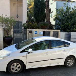 מכונית חונה מול בית עם גינה ועצים