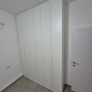 ארון בגדים לבן עם דלתות סגורות בחדר ריק