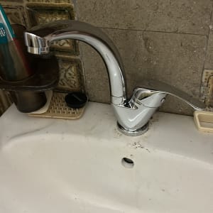 ברז כרום מותקן על כיור לבן עם ניקוז