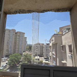 רשת בטיחות מותקנת בחלון עם נוף לבניינים