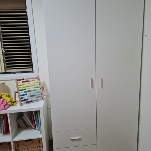 ארון לבן עם שתי דלתות ומדפים ליד חלון