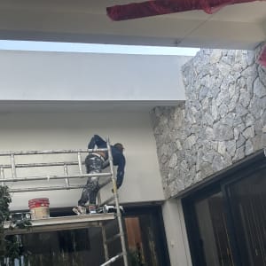 אדם צובע קיר על פיגום עם דלי צבע