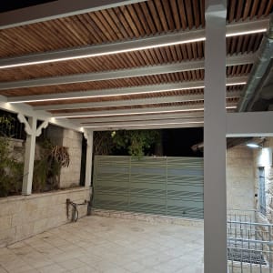 פרגולה מעץ עם תאורה מעל מרפסת מרוצפת